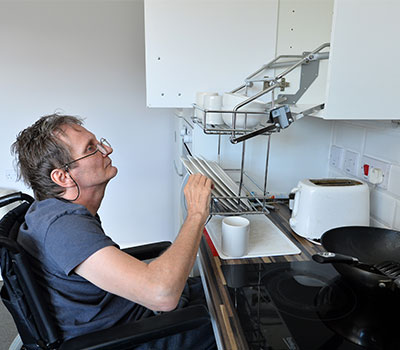 accessible housing - a man in a wheelchair uses accessible kitchen